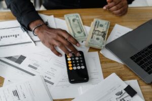 Overhead view of financial documents with calculator, cash, and laptop for financial planning.